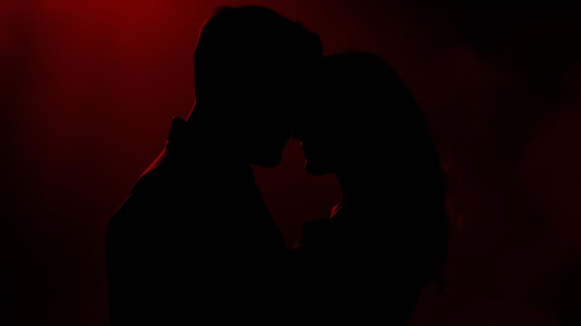Sensuellt par i siluett mot rött ljus